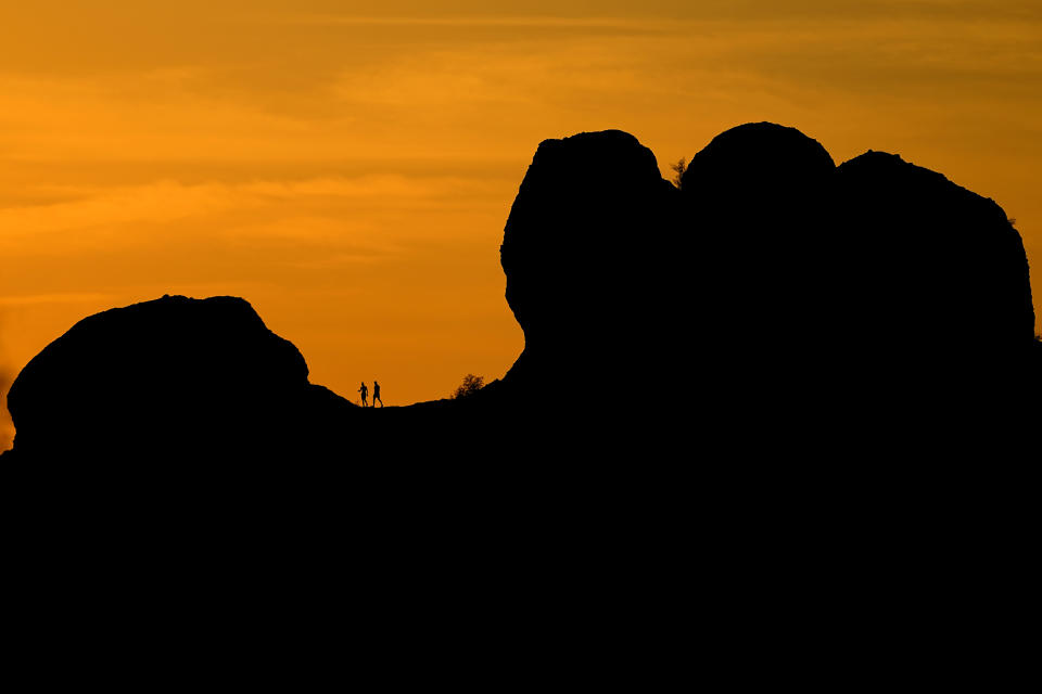 A couple hikes at Papago Park at dusk, Friday, July 14, 2023 in Phoenix. Phoenix marked the city’s 15th consecutive day of 110 degrees Fahrenheit (43.3 degrees Celsius) or higher temperatures on Friday. (AP Photo/Matt York)
