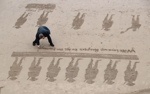 Volunteers create beach drawings at the Pages of the Sea commemorative event at Blackpool, - Credit: PA