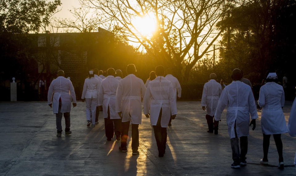 Una brigada de profesionales de la salud, que se ofrecieron como voluntarios para viajar a las Indias Occidentales, caminan de regreso a su campus después de posar para los fotógrafos en La Habana, Cuba, el sábado 28 de marzo de 2020. (AP Foto / Ismael Francisco)