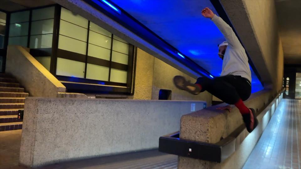 Someone doing parkour over a stone wall