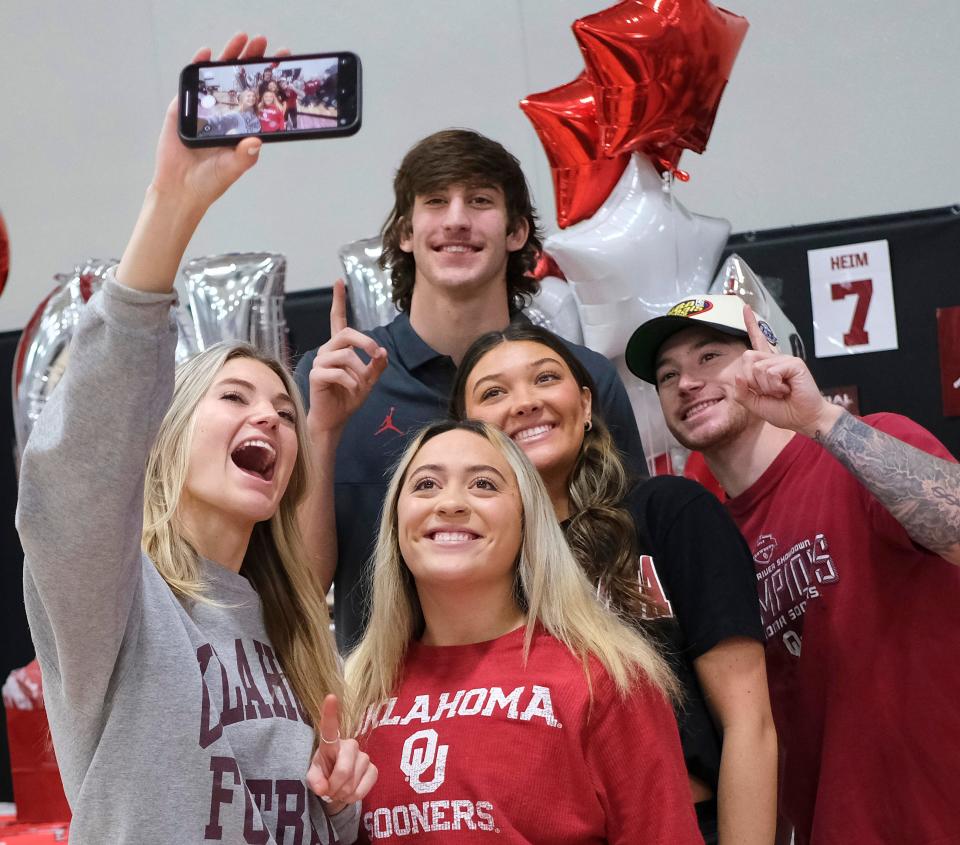 Taylor Heim poses with family for a selfie taken by his sister Morgan Heim, (gray), with Reghan Kyle (red) Zoe Grigg (black), girlfriend of older brother Tim Heim (in hat). Taylor Heim celebrates committing to OU during Bethany High School signing day celebrations in the gymnasium Friday, February 3, 2023.