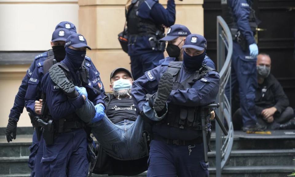 Six police officers carrying a man down steps.