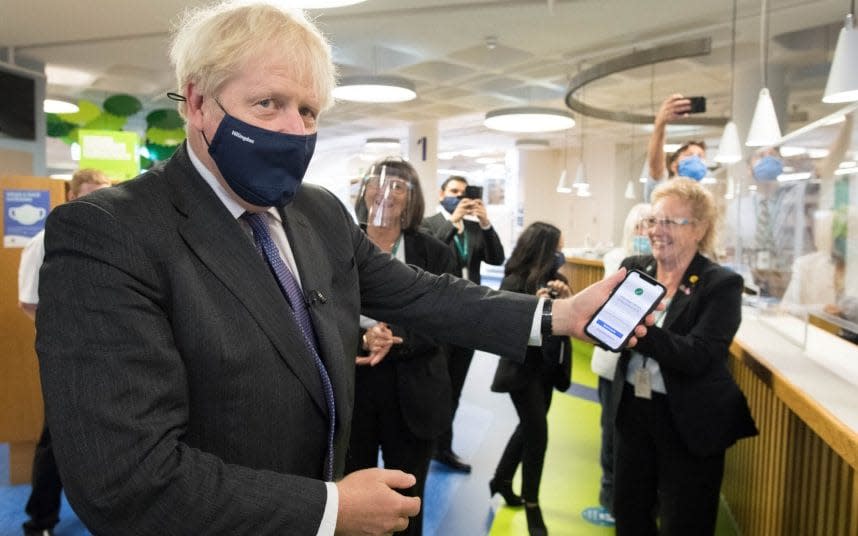 Boris Johnson, facing calls for a national lockdown, uses the NHS Covid-19 app - PA
