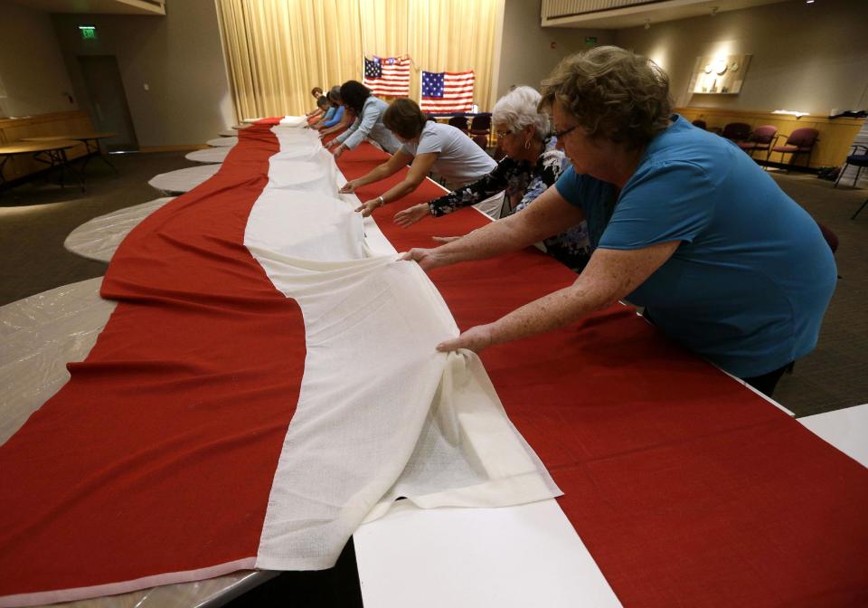 In this July 22, 2013 picture, volunteers line up stripes that, when hand-stitched together, will be part of a replica of the star-spangled banner in Baltimore. It was 200 years ago this summer that a Baltimore flag-maker stitched the flag that inspired America’s national anthem. Now, hundreds of people are helping to recreate the star-spangled banner. The project began July 4 in Baltimore, and it is expected to take volunteers six weeks to hand sew the estimated 150,000 stitches in the famous flag. When finished, it will be about a quarter of the size of a basketball court. (AP Photo/Patrick Semansky)