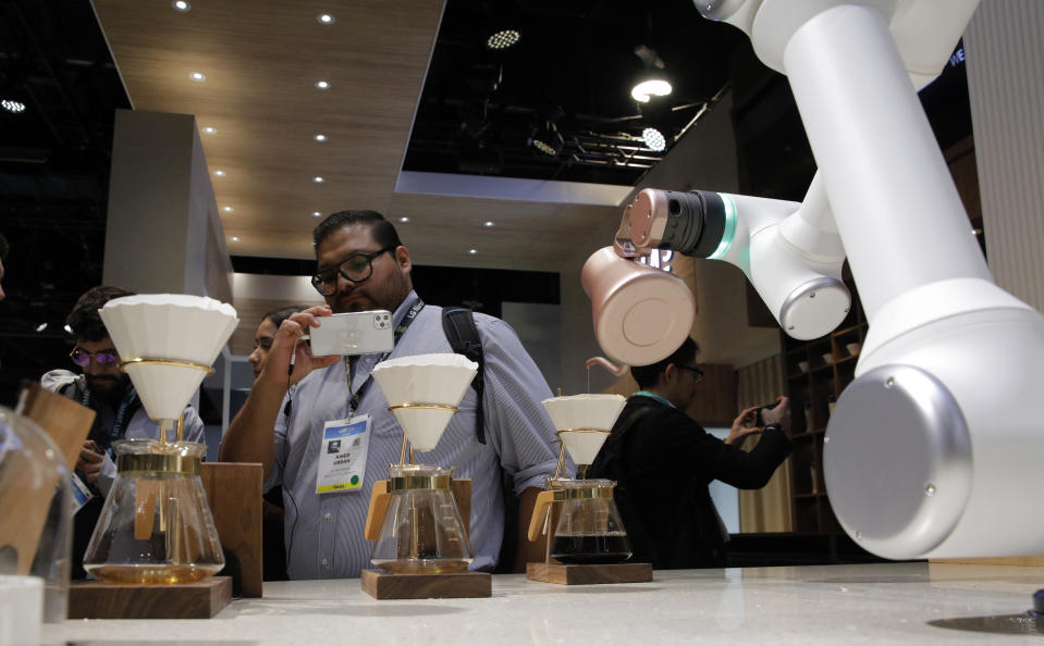 An attendee looks as an LG CLOi CoBot Barista makes coffee in a mock restaurant setting at the LG booth during the CES tech show, Tuesday, Jan. 7, 2020, in Las Vegas. (AP Photo/John Locher)