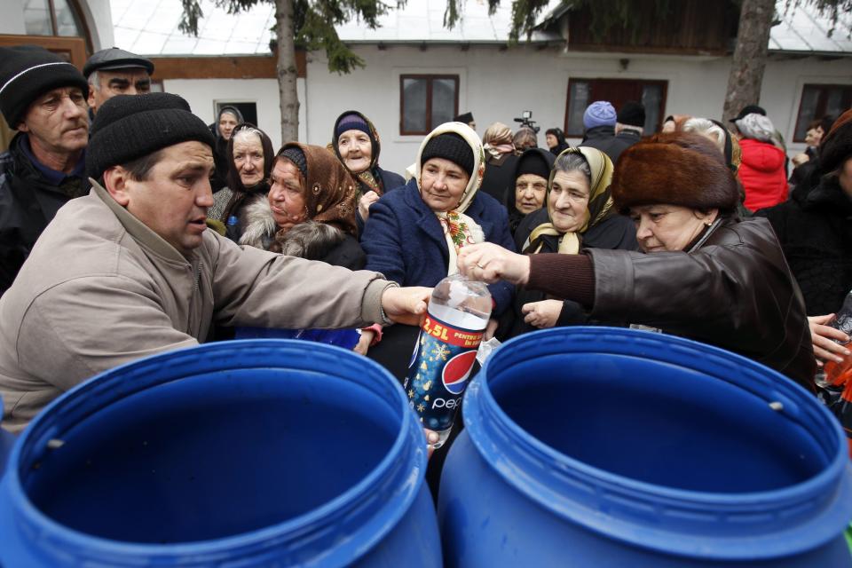 Orthodox believers take the holy water at a church on Epiphany Day in the Romanian village of Pietrosani, 45 km (28 miles) north of Bucharest, January 6, 2014. Epiphany Day falls on January 6 every year and it celebrates the end of Christmas festivities in Romania. REUTERS/Bogdan Cristel (ROMANIA - Tags: SOCIETY RELIGION)