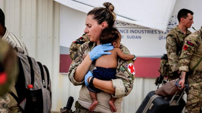 An Army paramedic holds a baby during evacuation of British nationals in Sudan