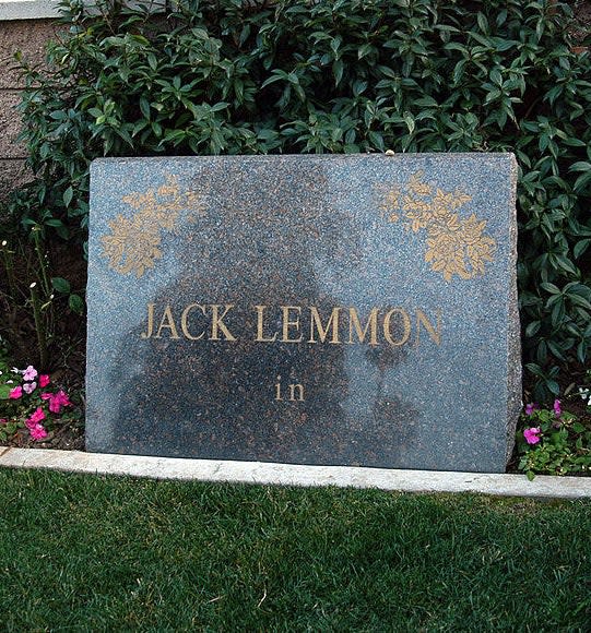 A simple stone marker with Lemmon's name and the word "in" below it over a plot of grass