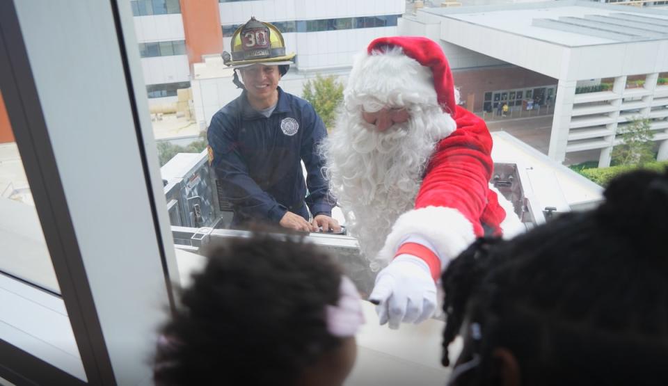 Firefighters and police officers surprised children and their families in the sixth annual Holiday Elf rappelling event.