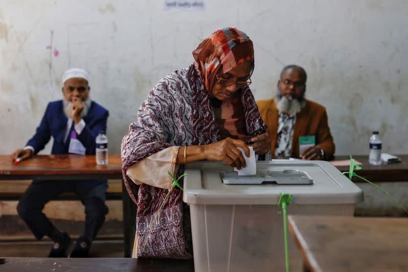 An elderly woman puts ballot paper inside a ballot box after casting her vote in the morning during the 12th general election in Dhaka