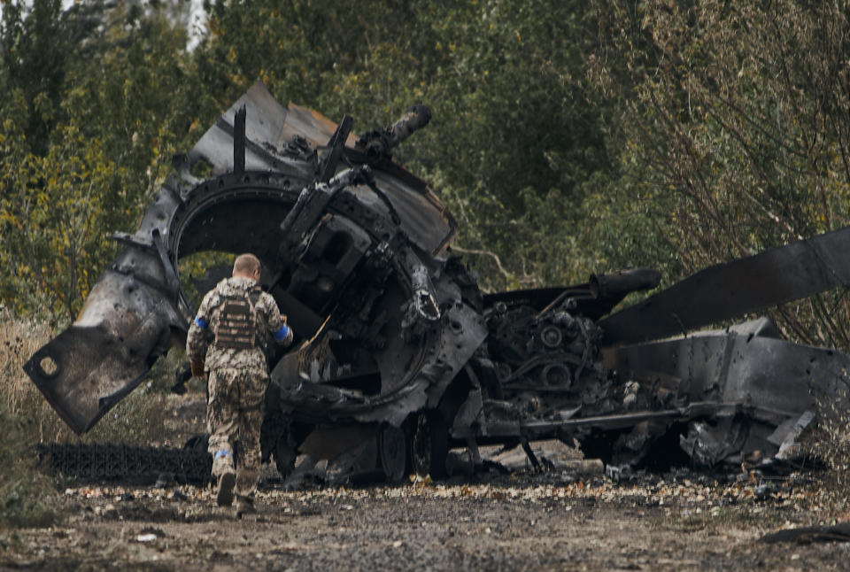 A Ukrainian soldier passes by a Russian tank damaged in a battle in a just freed territory in the Kharkiv region. (Reuters)
