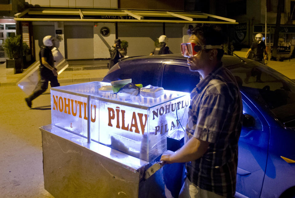 A street food vendor wears goggles to protect himself from tear gas while standing next to his cart during clashes between Turkish riot police and protesters in Ankara, Turkey, Tuesday, June 11, 2013. Turkey's Prime Minister Recep Tayyip Erdogan will meet with a group of protesters occupying Istanbul's central Taksim Square this week, Deputy Prime minister Bulent Arinc said Monday, as the government sought a way out of the impasse that has led to hundreds of protests in dozens of cities. (AP Photo/Vadim Ghirda)