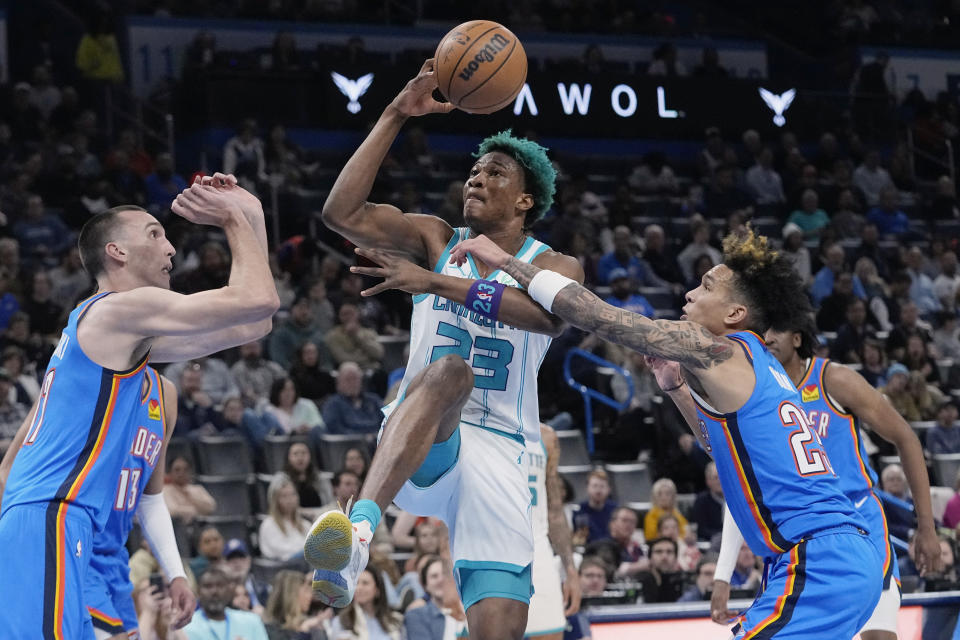 Charlotte Hornets forward Kai Jones (23) is fouled by Oklahoma City Thunder guard Tre Mann, right, as he drives between Mann and forward Aleksej Pokusevski, left, in the first half of an NBA basketball game Tuesday, March 28, 2023, in Oklahoma City. (AP Photo/Sue Ogrocki)