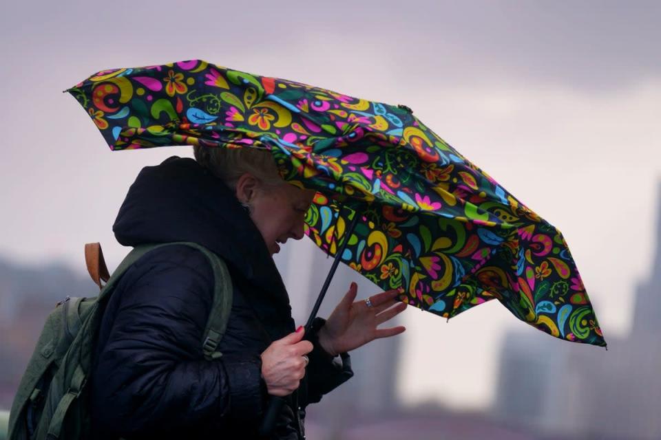 A woman struggles with an umbrella as she walks over Westminster Bridge during high winds and wet weather (Victoria Jones/PA) (PA Wire)