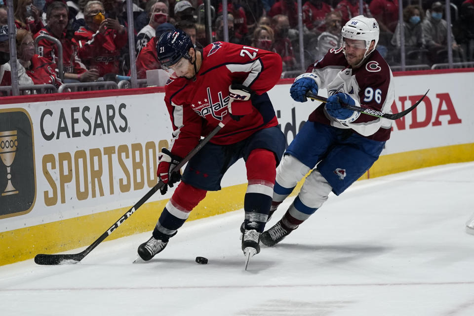 Washington Capitals right wing Garnet Hathaway (21) and Colorado Avalanche right wing Mikko Rantanen (96) vie for the puck in the first period of an NHL hockey game Tuesday, Oct. 19, 2021, in Washington. (AP Photo/Alex Brandon)