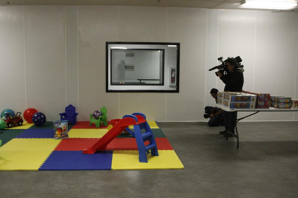 Video journalists record images of never-touched toys during a Border Patrol tour of an immigration holding facility, Tuesday, Feb. 25, 2020, in El Paso, Texas. The complex of modular buildings is expected to open next week. Itcan house and process 1,040 and will replace tents hastily erected for processing last spring. (AP Photo/Cedar Attanasio)