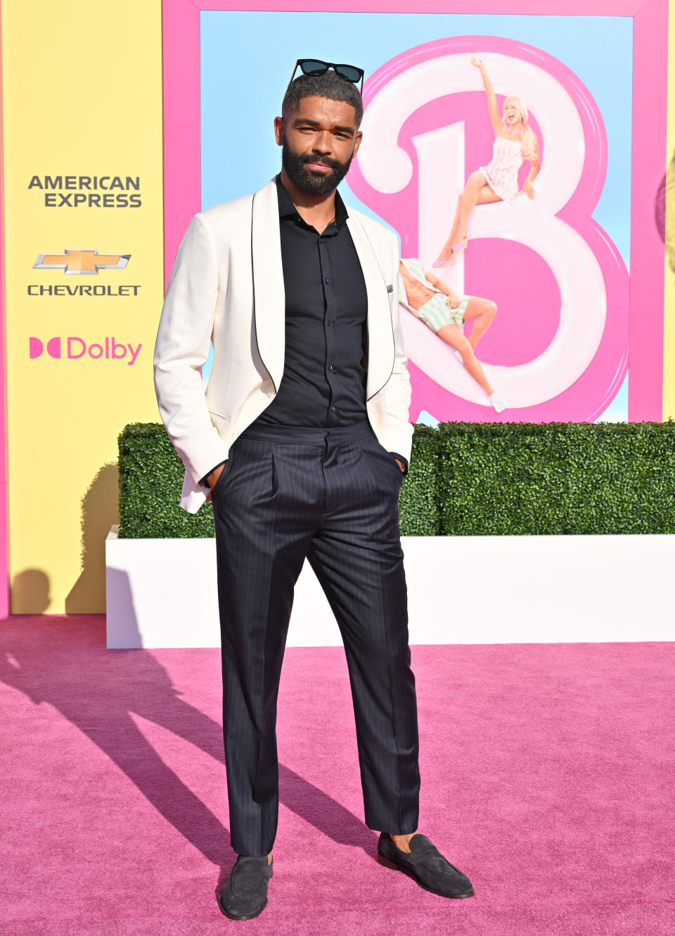 In a light-colored suit jacket and dark pants and top