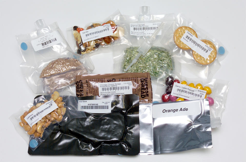 A variety of packaged and bagged foods lie on a white table.