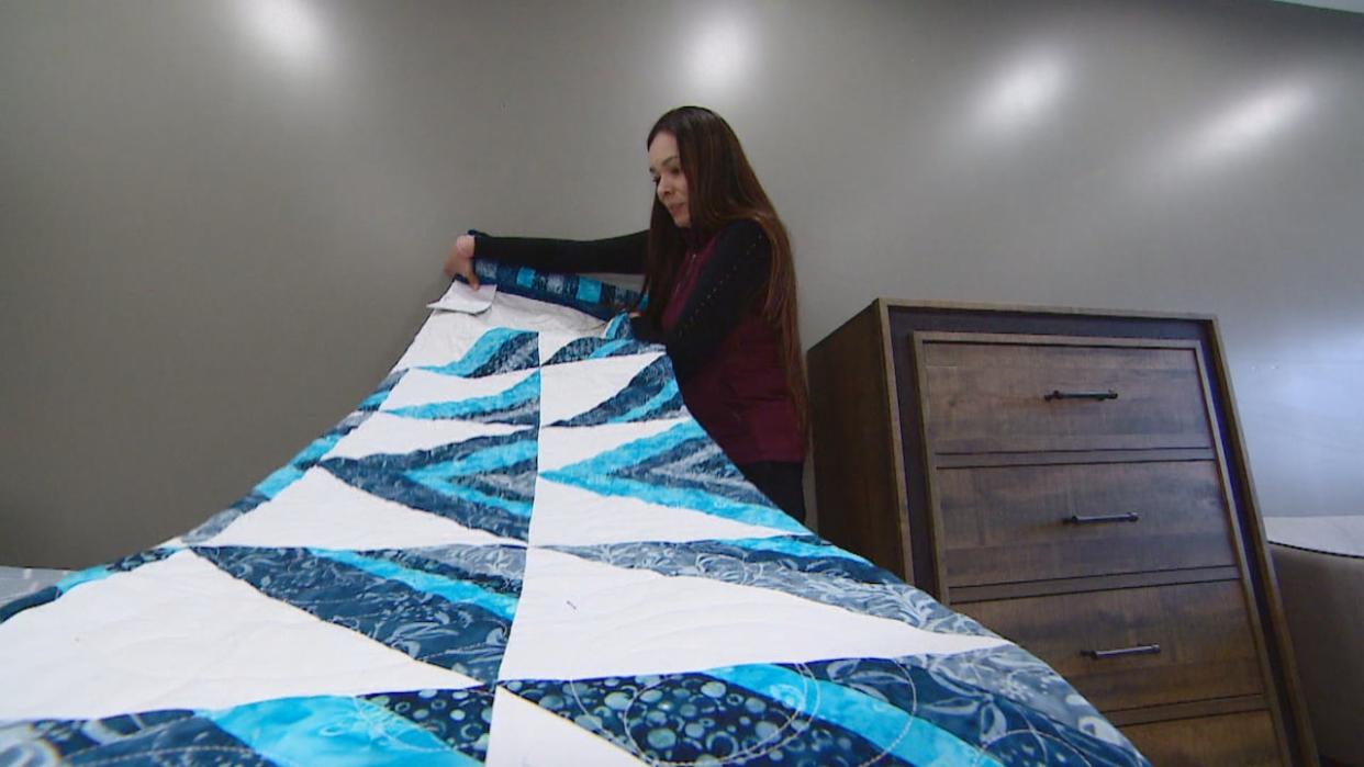 Crystal LaPlante folds a quilt meant for one of the tenants of Īkwēskīcik iskwēwak, a transitional home in Saskatoon for women leaving jail. The handmade blanket is a meant as a gesture of love and support. (Don Somers/CBC - image credit)