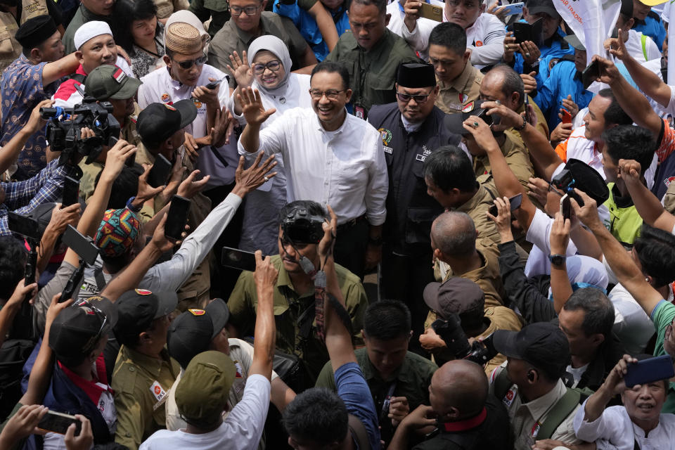 Presidential candidate Anies Baswedan, top center, and his wife Fery Farhati Ganis waves at the media upon arrival at a stadium for a campaign rally in Jakarta, Indonesia, Tuesday, Nov. 28, 2023. Candidates officially began their campaign for next year's election which will determine who will succeed President Joko Widodo who is now serving his second and final term. (AP Photo/Achmad Ibrahim)