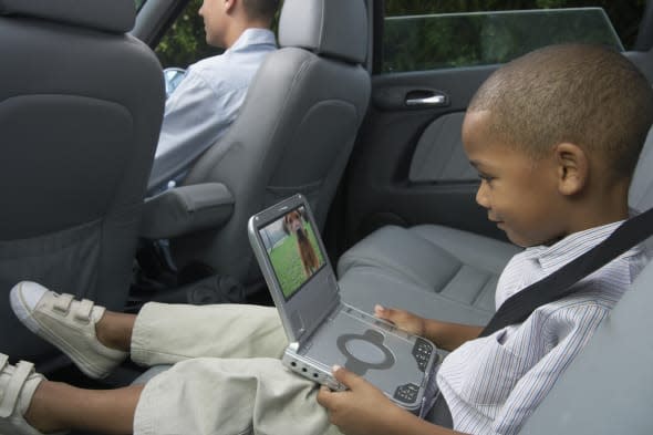 Father and son (5-7) in car (focus on boy using portable DVD player)