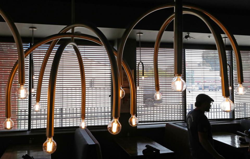 Barrelhouse owner Nick Jones is framed by the custom chandeliers hanging in the dining area of his restaurant in Akron.