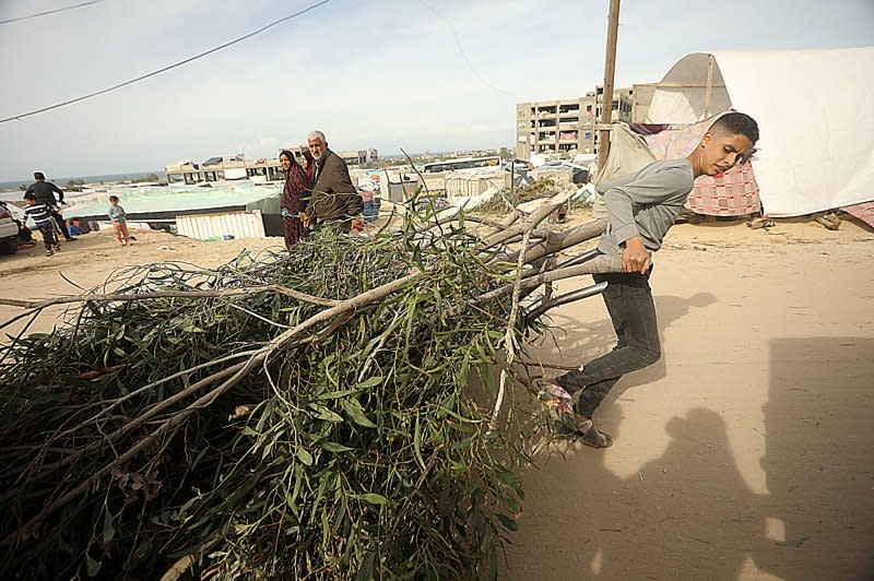 A Palestinian boy drags firewood for campfires while walking past tents erected by Palestinians displaced by intense Israeli bombardment on the Gaza Strip in open areas near the Egyptian border in Rafah on Sunday. Photo by Ismael Mohamad/UPI