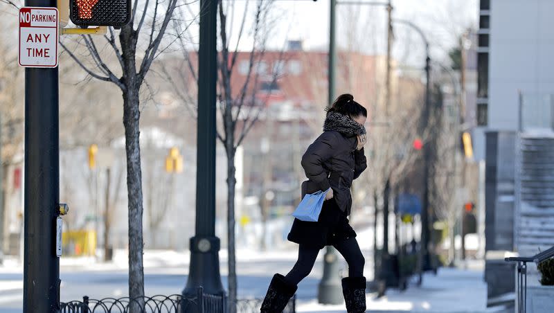 A pedestrian shields herself from the cold wind while walking in Atlanta, Wednesday, Jan. 17, 2018. Ohio State University, Iowa State University and others have reported that the safest way to get to where you need to go even in the iciest of conditions is to walk like a penguin.