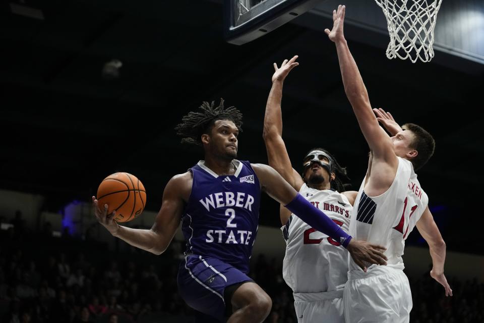 From left to right, Weber State forward Dillon Jones passes the ball while defended by Saint Mary’s forward Mason Forbes and center Mitchell Saxen during the second half of an NCAA college basketball game Sunday, Nov. 12, 2023, in Moraga, Calif. | Godofredo A. Vásquez, Associated Press