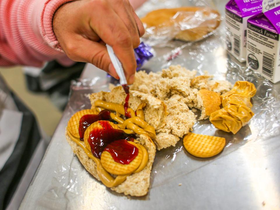 An immigrant inmate prepares breakfast at the Maricopa County Tent City jail on March 11, 2013 in Phoenix, Arizona. Peanut butter and jelly sandwiches are the standard daily breakfast at the facility. The tent jail, run by Maricopa County Sheriff Joe Arpaio, houses undocumented immigrants who are serving up to one year after being convicted of crime in the county. Although many of immigrants have lived in the U.S for years, often with families, most will be deported to Mexico after serving their sentences. (Photo by John Moore/Getty Images)