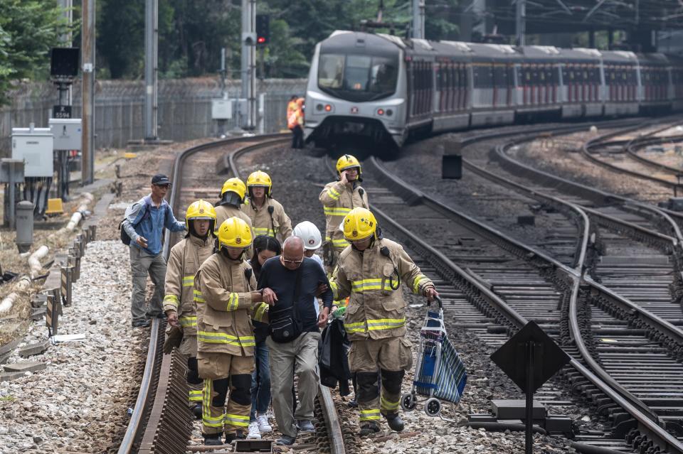 A man is escorted by firemen on the train tracks at Sha Tin MTR station due to the disruption of the train services in Hong Kong on November 12, 2019. | PHILIP FONG—AFP via Getty Images