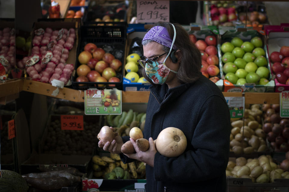Victoria Martinez, 44, buys vegetables to cook the food for her family at a market in Barcelona, Spain, Monday, Feb. 8, 2021. By May this year, barring any surprises, Martinez will complete a change of both gender and identity at a civil registry in Barcelona, finally closing a patience-wearing chapter that has been stretched during the pandemic. The process, in her own words, has also been “humiliating.” (AP Photo/Emilio Morenatti)