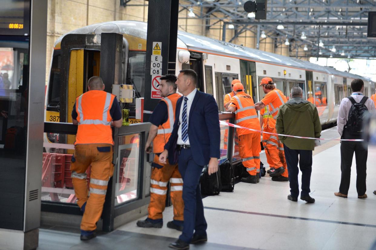 Railway staff at London's King's Cross station assess the train: PA