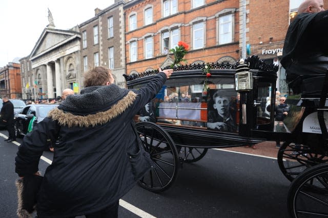 Flowers are thrown at the hearse as the funeral procession of Shane MacGowan makes its way through the streets of Dublin