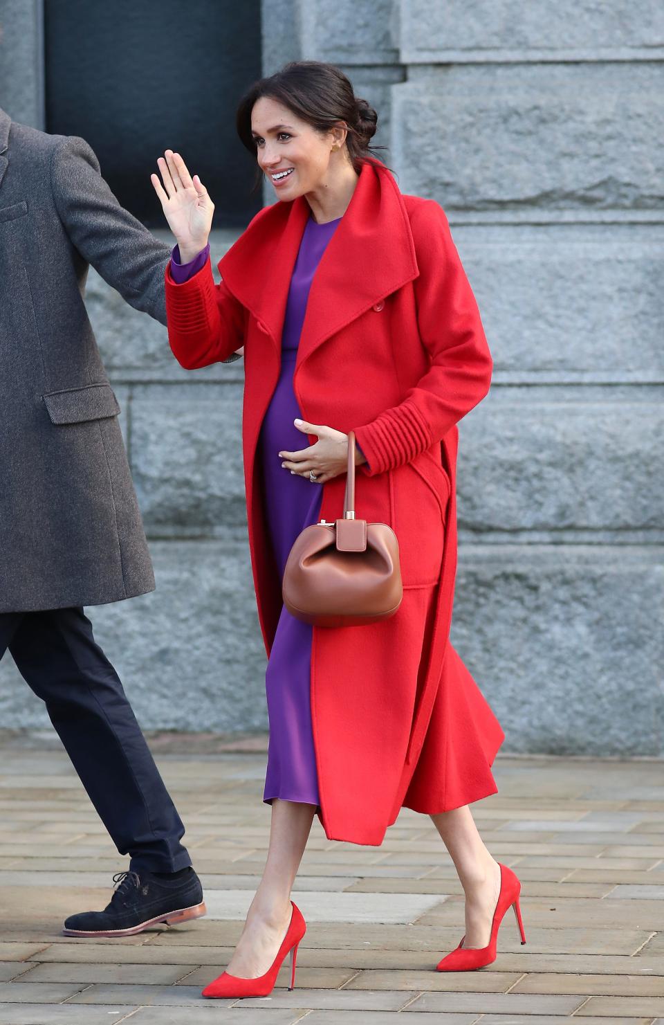 Meghan Markle wears a purple dress and red coat in January 2019.