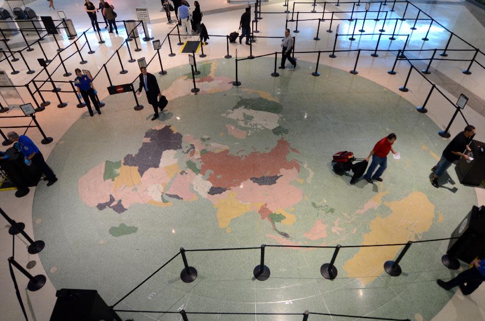 In this photo taken Oct. 29, 2013 in Dallas, passengers walk to a security checkpoint over a map of the world at Love Field. The map was one of the items preserved during an ongoing renovation of the terminal and was in the same location on Nov. 22, 1963 when Air Force One landed with President John F. Kennedy aboard. (AP Photo/Benny Snyder)