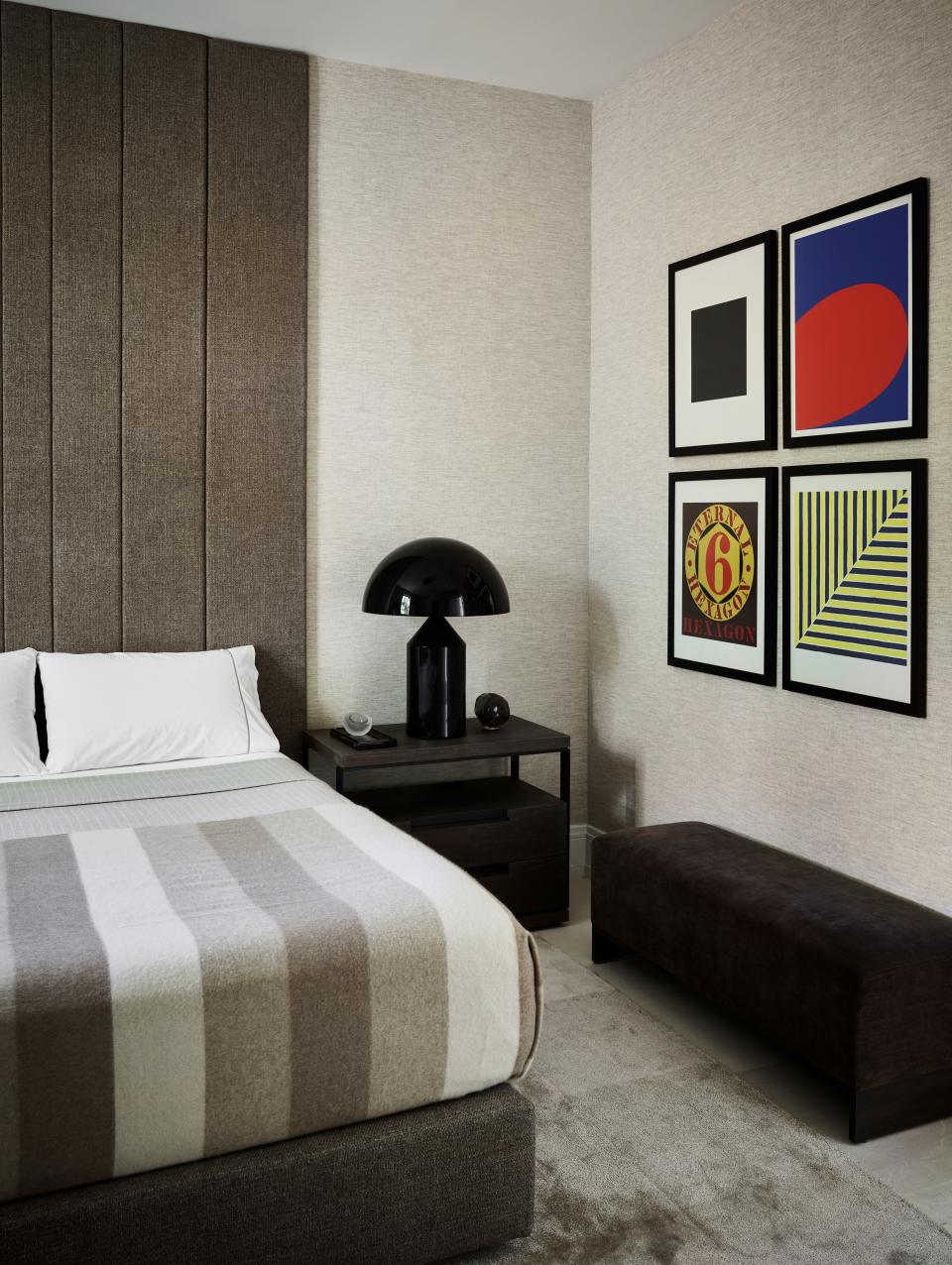 There are two guest bedrooms on the main floor of the home. This one, like the master bedroom, also features a custom headboard and linens by Matouk. Pops of color are provided by the quartet of Robert Indiana prints, and texture is added by the Phillip Jeffries wall covering and the custom carpet by Art and Loom.