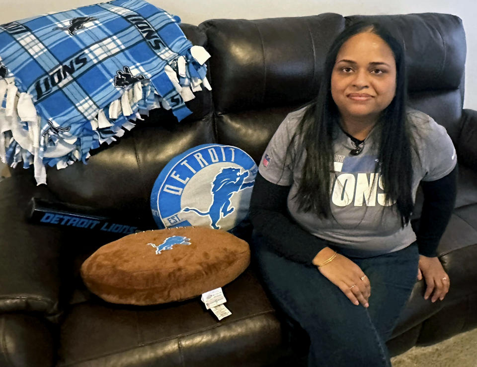 Sweta Patel sits in her Canton, Mich., home with Detroit Lions pillows, a blanket and speaker Thursday, Jan. 18, 2024. Patel, from India, became an NFL football Lions fan about a decade ago and is a season-ticket holder who has developed personal connections with the team. (AP Photo/Larry Lage)