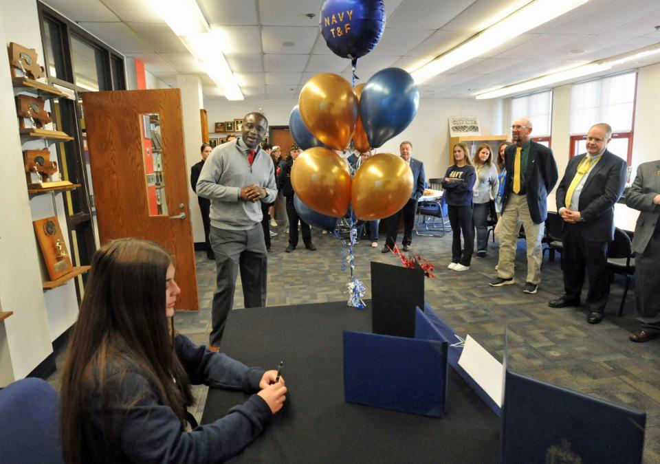 North Quincy High School Athletic Director J.J. Niamkey congratulates North Quincy High School senior Kiera Sleiman, left, as she prepares to sign her acceptance certificate to the United States Naval Academy during a ceremony at North Quincy High School on Friday, April 29, 2022.