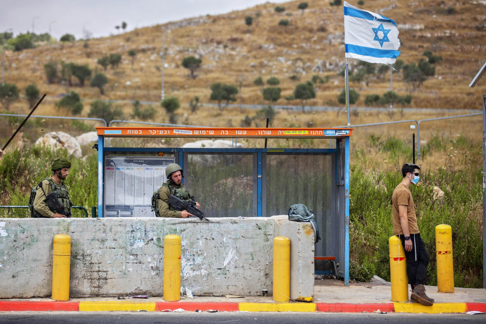 Israeli soldiers guard a bus station at the Tapuach junction next to the West Bank city of Nablus, Tuesday, June 30, 2020. Israeli Prime Minister Benjamin Netanyahu appears determined to carry out his pledge to begin annexing parts of the occupied West Bank, possibly as soon as Wednesday. (AP Photo/Oded Balilty)