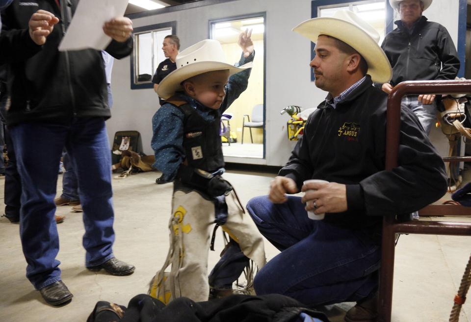 CeJay Jones practices holding on with his father Chris looking on before he competed in the mini bull riding competition at the 108th National Western Stock Show in Denver