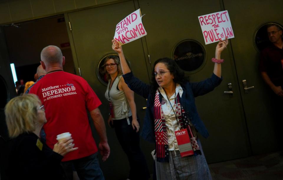 Jazmine Early, of Sterling Heights, holds up signs at the entrance to the hall just before the start of the 2022 Michigan Republican Party's nominating convention on Aug. 27, 2022 in the Lansing Center in Lansing.