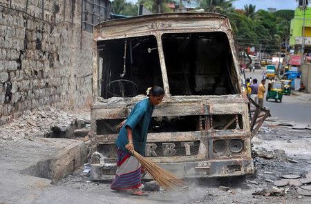 A municipal worker sweeps around the charred remains of a lorry set ablaze during the violent protests after Supreme Court ordered Karnataka to release water from the Cauvery river to the neighbouring state of Tamil Nadu, in Bengaluru, India, September 14, 2016. REUTERS/Abhishek N. Chinnappa