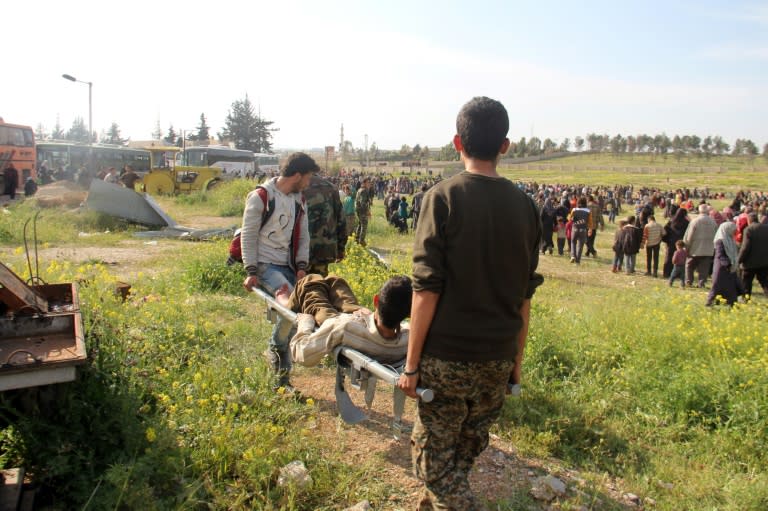 A wounded Syrian, evacuated from two besieged government-held towns of Fuaa and Kafraya, is carried into a field near the site of a suicide car bombing that targeted their buses in Rashidin, west of Aleppo, on April 15, 2017