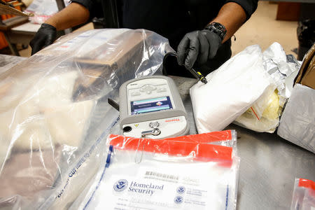 U.S. Customs and Border Protection officer Mohammed Rahman uses a laser to scan packages for contraband in a detention room at the JFK mail facility in New York, U.S., August 28, 2018. REUTERS/Jill Kitchener