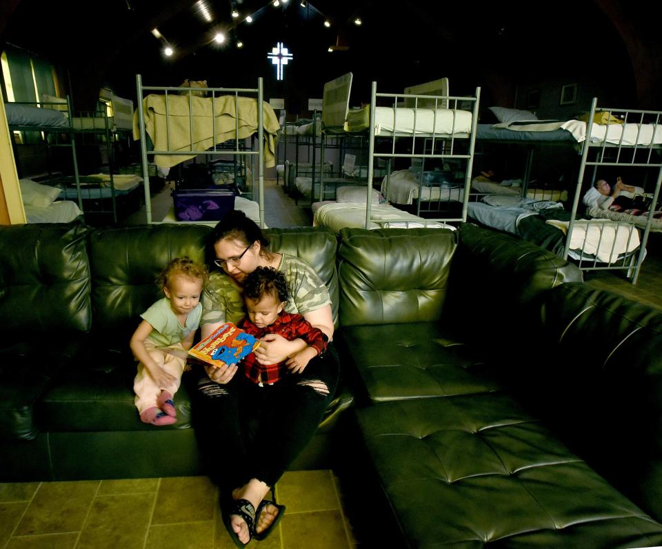 Romy Kelly reads a story to her daughter Violet Daykin, 3, and son Daylen Daykin, 2, in the lounge area where the women sleep at the Oaks Shelter in Monroe.