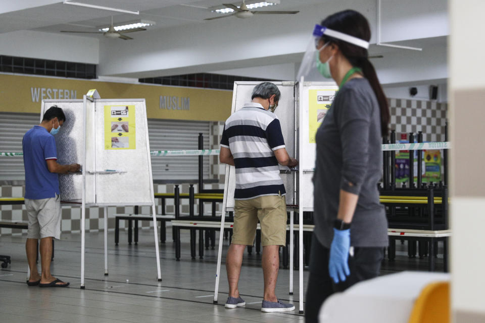 Voters, wearing face masks, cast their votes at the Chung Cheng High School polling center in Singapore, Friday, July 10, 2020. Wearing masks and plastic gloves, Singaporeans began voting in a general election that is expected to return Prime Minister Lee Hsien Loong's long-governing party to power. (AP Photo)