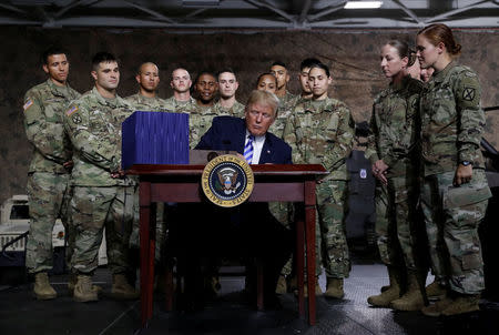 U.S. President Donald Trump holds up the National Defense Authorization Act after signing it in front of soldiers from the U.S. Army's 10th Mountain Division at Fort Drum, New York, U.S., August 13, 2018. REUTERS/Carlos Barria