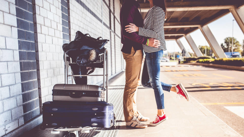 Young couple kissing outside airport.