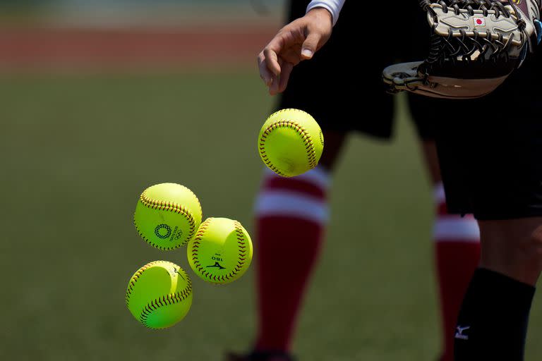 Una jugadora japonesa de softball tira pelotas dentro de una canasta durante una práctica en el estadio Azuma de Baseball.